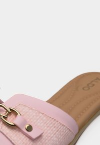 Sandale rose à enfiler pour femmes avec une sangle texturée, un détail de boucle dorée et une semelle intérieure rembourrée beige sur fond blanc.