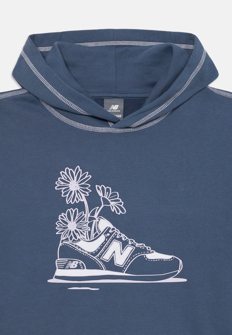 Un sweat à capuche bleu marine avec un cou à cordon, arborant un graphique blanc d'une basket avec des marguerites qui en poussent, souligné de détails fins.
