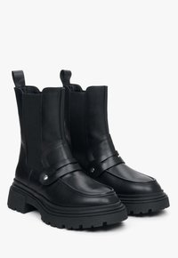 Czarne skórzane botki za kostkę z elastycznymi panelami bocznymi, zaokrąglonymi noskami i grubą podeszwą; posiadają dekoracyjną taśmę z ćwiekami.