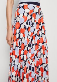 Gonna plissettata in blu navy, con un audace motivo astratto nei colori rosso, blu e bianco. Vita elasticizzata e tessuto leggero.