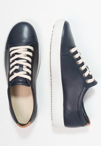 Marinblå lädersneakers med vita snören och gummisulor. Har en slät yta, rund tå och en minimalistisk design. Accenter i beige.