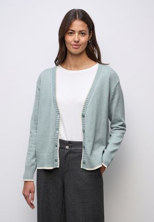 Cardigan en maille bleu clair avec une texture côtelée, présentant un bord contrastant crème, des boutons devant et des épaules tombantes.