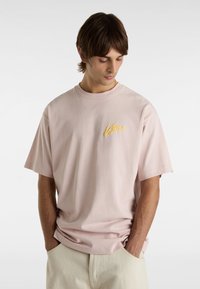 Helles rosa T-Shirt mit kurzen Ärmeln aus Baumwolle, mit einem gelben gestickten Logo auf der Brust und einem lässigen Schnitt.