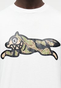 Λευκό βαμβακερό μπλουζάκι με σχέδιο κινούμενου ζώου με καμουφλάζ σε καρικατουρίστικο στυλ, με υπερβολικά χαρακτηριστικά προσώπου και έντονες περιγράμματα.