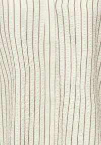 Tissu crème avec de fines rayures verticales marron et un motif en relief à pois subtil.