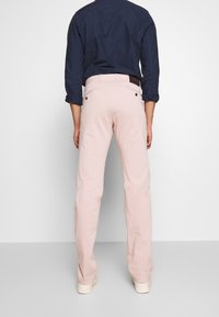 Jasnoróżowe, proste spodnie wykonane z bawełny. Posiadają dwie tylne kieszenie i szlufki na pasek. Nosi się je z ciemnoniebieską, długorękawową koszulą.