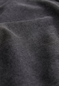Close-up of soft, dark gray knit fabric with visible texture and gentle folds.