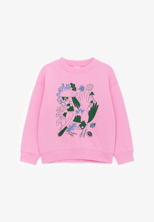 Różowa bluza z długim rękawem z zielono-niebieską abstrakcyjną grafiką ptaków, liści, rąk, kwiatów i owadów na przodzie.