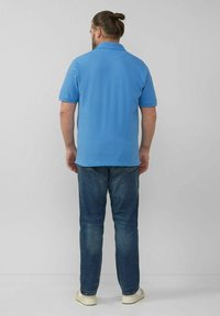 Helles blaues Poloshirt mit kurzen Ärmeln und Kragen, kombiniert mit Jeans und weißen Sneakers. Sichtbare Nähte.