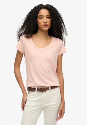 Light pink, short-sleeve t-shirt with a scoop neck, made from soft fabric, worn with cream-colored pants and a brown belt.