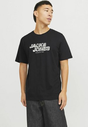 Sort bomulds t-shirt med en hvid grafisk trykning af "JACK & JONES" og "Etableret 1990" i en afslappet blokskrift. Korte ærmer.