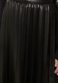 Faltender schwarzer Lederrock mit vertikalen Falten, glatter Textur und angepasstem Taillenbund. Das Detail zeigt eine Nahaufnahme des Stoffes und des Designs.