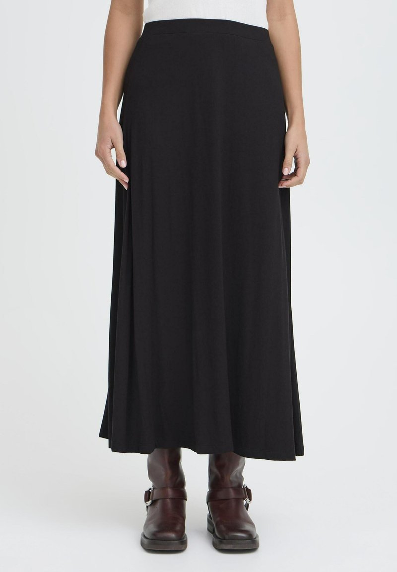 Črna maxi krila iz mehkega blaga z širokim, gladkim pasom. Ima tekoč dizajn, ki se razteza do gležnjev, v kombinaciji z rjavimi škornji.