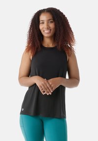 Top senza maniche nero con una vestibilità comoda, realizzato in tessuto morbido. Dettaglio logo minimale all'orlo. Abbinato a leggings sportivi color teal.