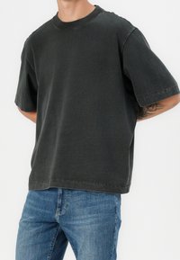 Camiseta de manga corta en gris oscuro con escote redondo y ajuste relajado. Material de algodón con textura suave y detalles sutiles de costura.