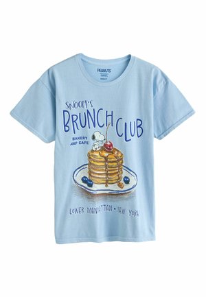 Svetlomodré tričko so Snoopym sediacim na hromade palaciniek s čerešňou a čučoriedkami na tanieri, text "Snoopy’s Brunch Club."