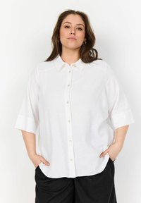 White linen button-up shirt with short sleeves, straight cut, and a classic collar. Features a front button closure and subtle texture.