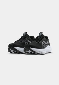 Zwarte sportieve schoenen met een witte zool. Mesh bovenwerk, afgeronde neus, gevoerde binnenzool en een kenmerkend zijlogo in het wit. Vetersluiting, flexibele buitenzool.