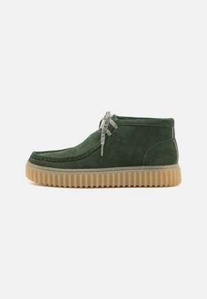 Groene suède enkellaarzen met een ronde neus, een gestructureerde rubberen zool en lichtgekleurde veters. Beschikt over zichtbare stiksels en een stevig ontwerp.