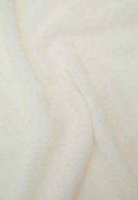 Tissu blanc, doux, avec une texture fine et transparente et un motif en maille subtil ; drapage lisse et apparence légère.