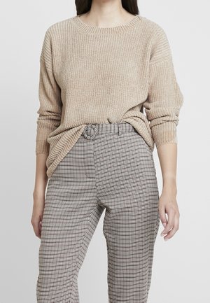 Beige textured knit sweater with a round neck, paired with high-waisted checkered pants featuring a belt. Slim fit with subtle patterns.
