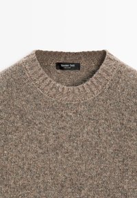 Brauner Strickpullover mit geripptem Halsausschnitt. Die Textur ist warm und weich und weist ein tonal abgestimmtes Muster auf. Etikett: Massimo Dutti.