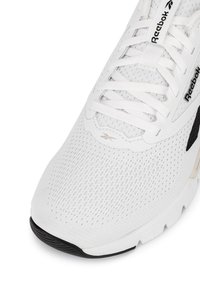 Biele športové topánky s priedušným sieťovaným zvrškom, plochými šnúrkami a jemnými čiernymi akcentmi. Podrážka je štruktúrovaná pre lepšiu priľnavosť.