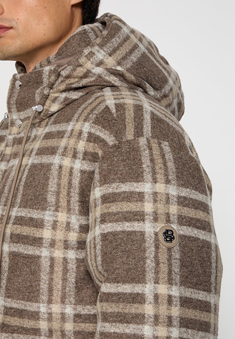 Veste à carreaux marron et beige avec capuche, texture semblable à de la laine, boutons-pression, accents de cordon de serrage et patch logo sur la manche.