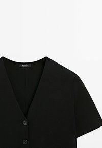 Top in maglia nera con scollatura a V, maniche corte e cinque bottoni neri. Tessuto liscio con un design aderente. Etichetta del marchio visibile.