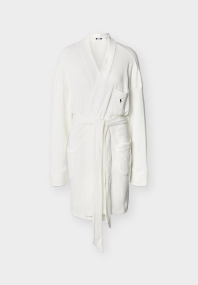 Λευκή βαμβακερή ρόμπα από ύφασμα πλεκτό τύπου βάφλ με γιακά κασκόλ, μακριά μανίκια, μπροστινή ζώνη, τρεις εξωτερικές τσέπες και μικρό κεντημένο λογότυπο στην τσέπη στο ύψος του στήθους.