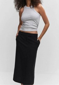 Haut sans manches gris et jupe noire mi-longue, présentant un design ajusté et des poches latérales, avec des textures lisses et un style minimaliste.