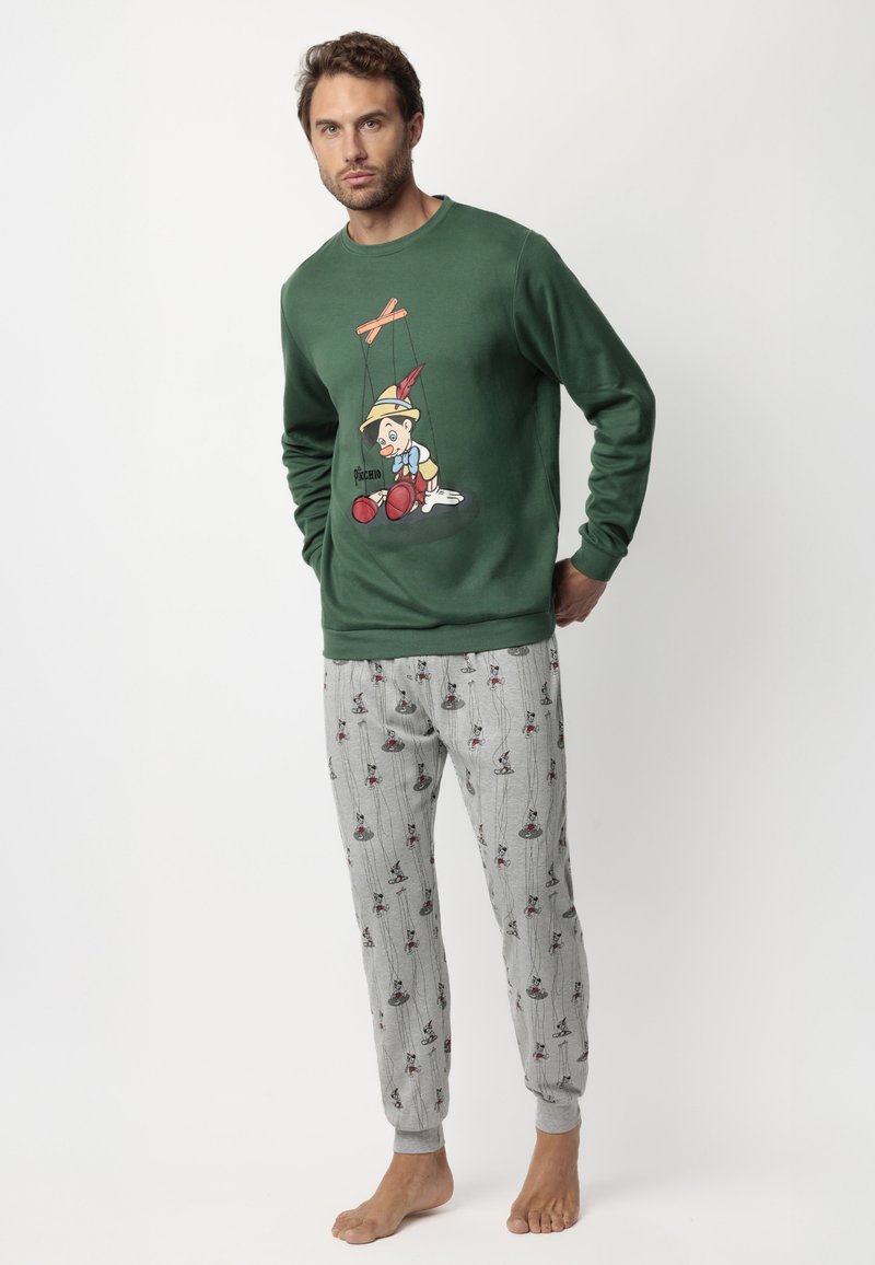 Sudadera verde con gráfico de Pinocho, combinada con pantalones de pijama grises que presentan un estampado repetitivo de figuras de marionetas. Material de algodón, ajuste casual.