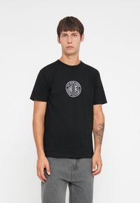 Black cotton t-shirt with short sleeves, featuring a circular graphic logo in white at the center and a crew neckline.