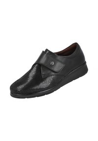 Zapato negro con una superficie texturizada y brillante; cuenta con una banda ancha y lisa con un acento circular y una suela acolchada.
