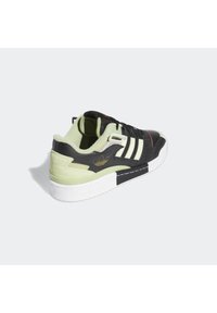 Svart och ljusgrön sneaker med tre vita ränder, i läder och textilmaterial, vadderad krage, vit sula och gyllene logotyp.