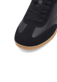 Mustad mustad, millel on sile nahk ülaosa, sametist varbakate ja kummist põhjaga. Sisaldab musti paelu ja detailset õmblust.