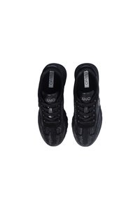 Sneaker atletiche nere con una tomaia in maglia testurizzata, punta rotonda e chiusura con lacci, accentuate da dettagli metallici e un logo.