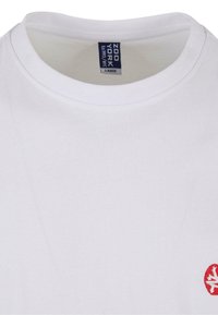 Hvid bomulds t-shirt med rund halsudskæring og et lille rødt logo på venstre side. Blød tekstur med lige syninger. Størrelse large.