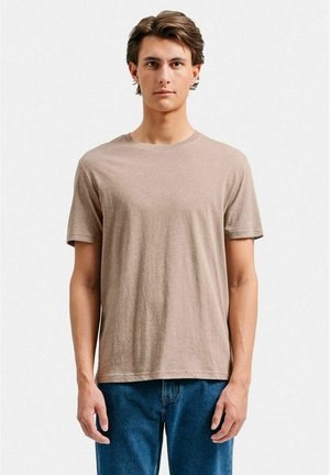 Lysebrun crew-neck t-shirt lavet af blødt stof, med korte ærmer og en afslappet pasform, parret med blå denimjeans.