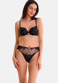 Zwart lingerieset met een gepadded beha met kanten overlay en bloemenpatroon, gecombineerd met hoge doorschijnende slipjes. Zachte textuur overal.
