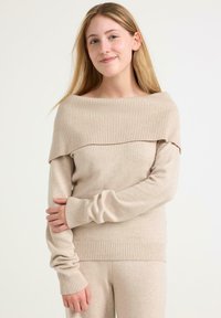 Beżowy sweter z prążkowanym, opadającym na ramiona krojem, długimi rękawami i prążkowanymi mankietami. Miękka tekstura o gładkim wykończeniu.