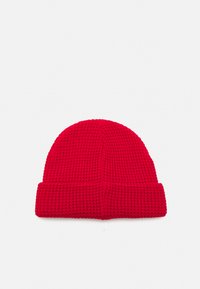 Căciulă tricotată roșie, cu un model texturat, având un tiv răsfrânt și un vârf rotund. Fabricată dintr-un material moale, elastic.