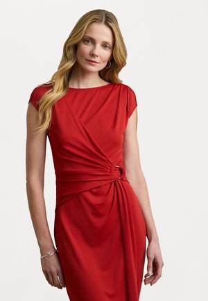Red dress with short sleeves, featuring a twisted design at the waist accented by metallic rings. Smooth fabric, knee-length fit.