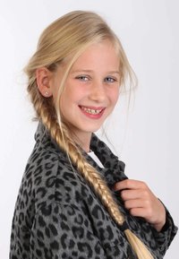 Kind met lang blond haar in een gevlochten haardos, draagt een grijze jasje met luipaardprint over een witte top, glimlachend met oorbellen.