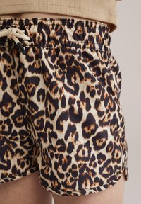 Leopardenmuster-Shorts in Beige, Braun und Schwarz. Elastischer Bund mit Kordelzug. Glatte Textur, oberhalb des Knies, seitliche Säume.