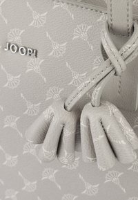 Borsa a mano grigia chiara con motivo floreale in rilievo, caratterizzata da un logo, dettagli texturizzati e manici annodati. Realizzata in materiale resistente.