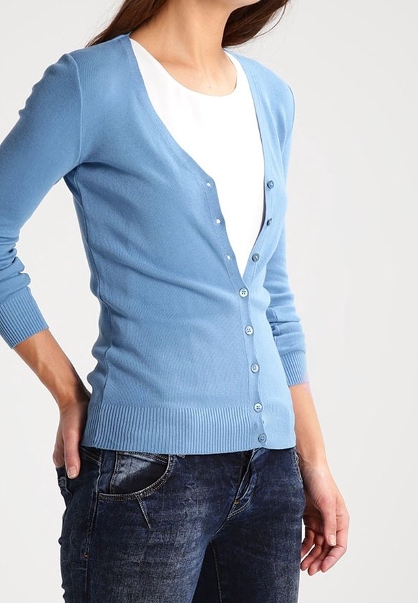 Ljusblå cardigan i mjukt stickat material, med V-ringning, full knappfront och ribbade ärmslut och fåll. Matchad med mörka jeans.