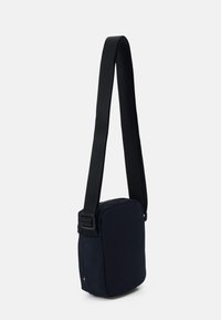 Borsa a tracolla blu navy realizzata in tessuto resistente, forma rettangolare, tracolla nera regolabile e discreto logo nella parte inferiore.