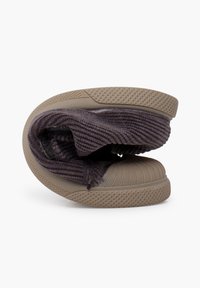 Chaussure pliable avec une semelle en caoutchouc beige texturé et un upper en tricot côtelé gris foncé. Le design présente un bout arrondi et une structure flexible.