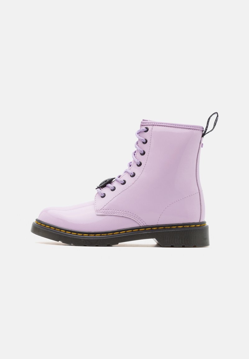 Lilac-värinen patenttina nahkakengät, joissa on mustat nauhat, paksu musta pohja ja erottuva ommel reunan ympäri. Takana lenkitappi.